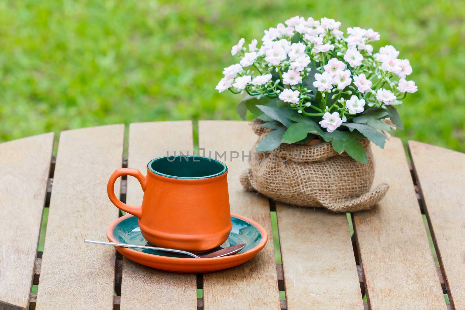 Clay cup with boquet of flower and grass in the background.