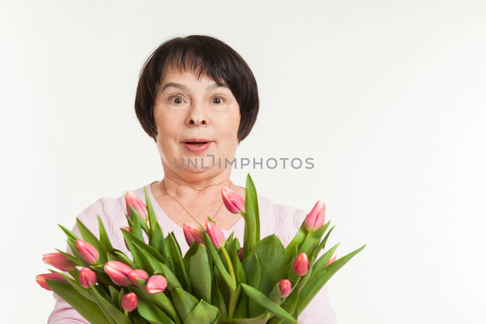 the beautiful mature woman is surprised to a bouquet of tulips