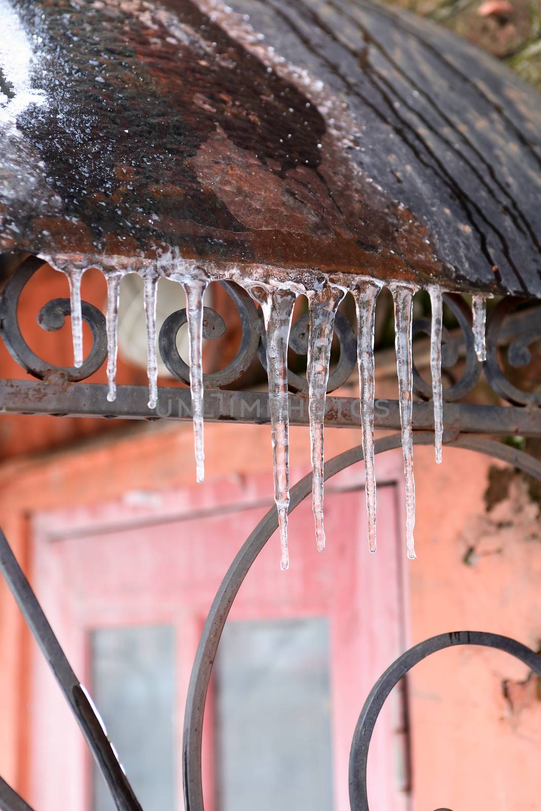 Spring beginning. Few icicles in a row on old metal roof