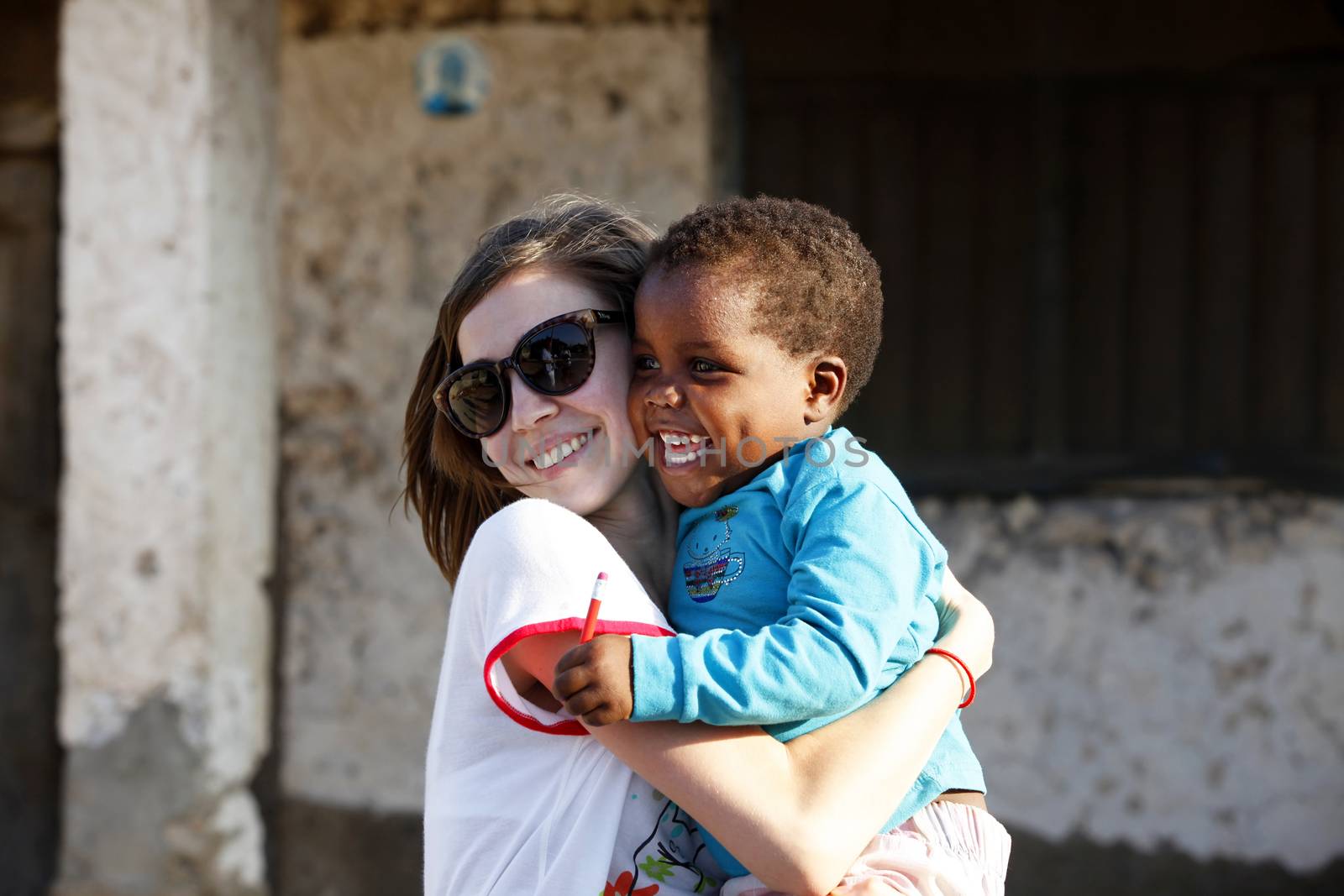 Zanzibar, Tanzania - January 8, 2016: Young woman - a tourist from Russia holds little African girl in her arms in Jambiani. Zanzibar