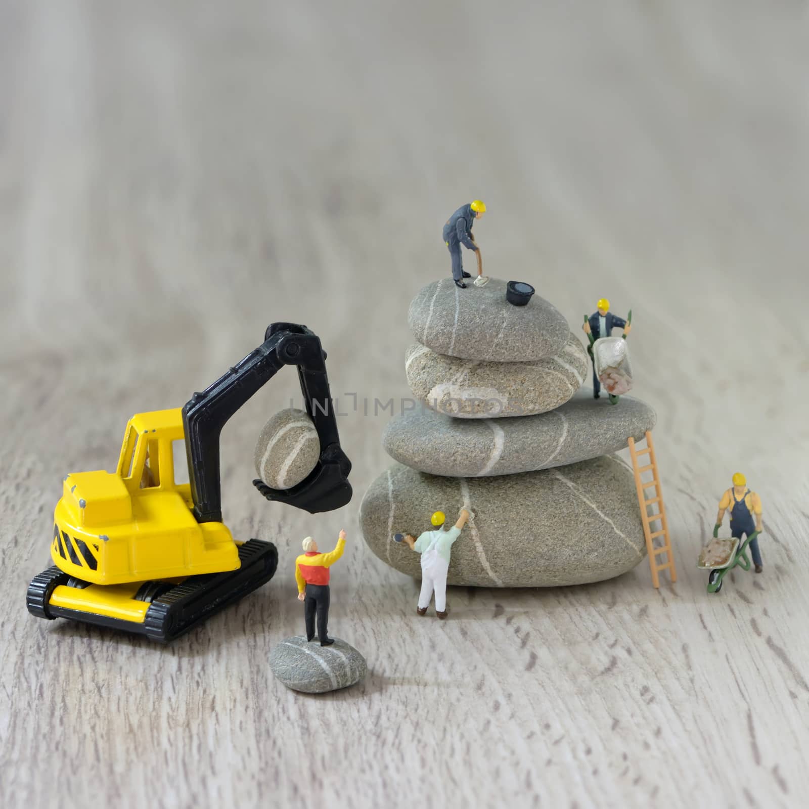 Construction site with miniature workers and pebbles