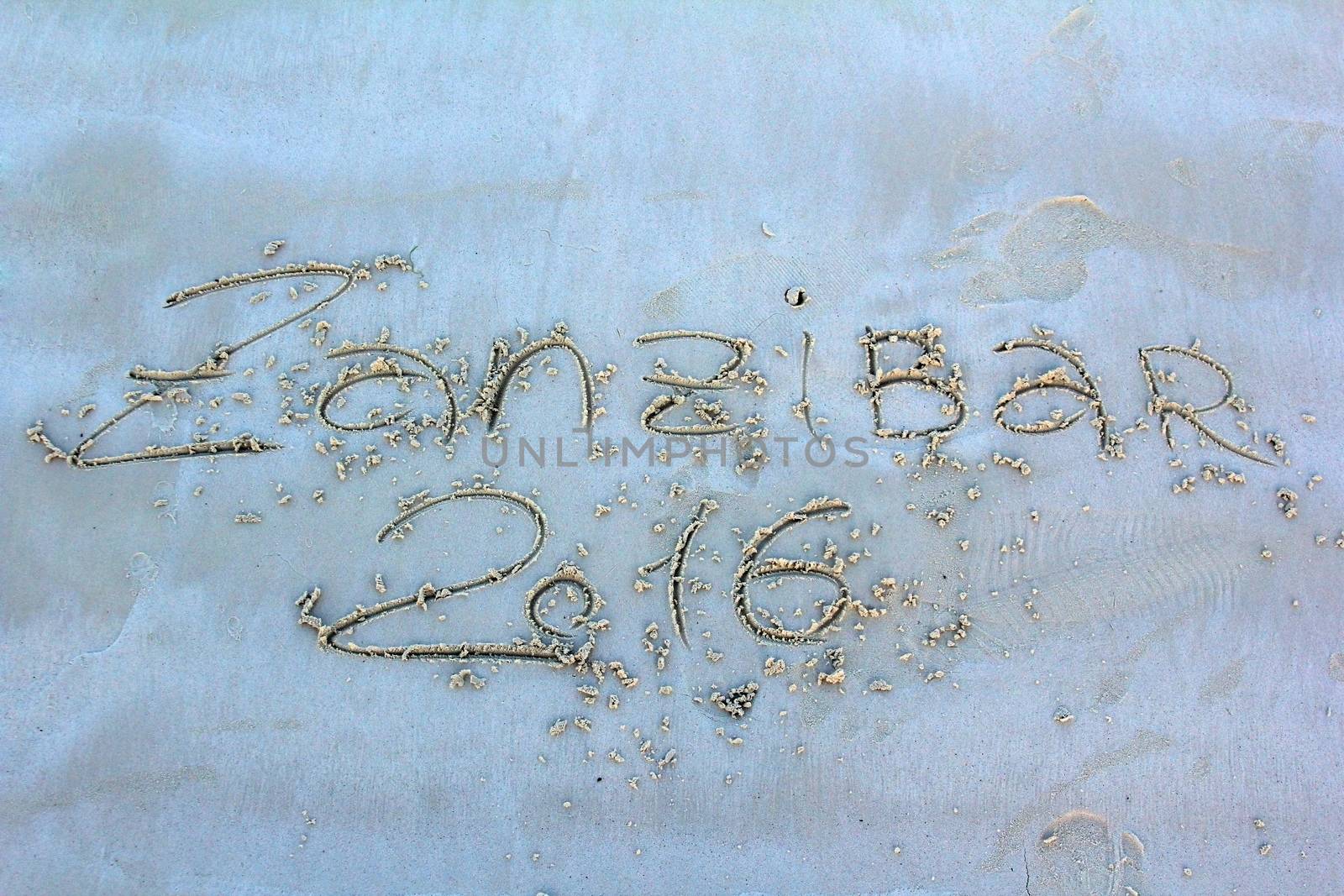 Zanzibar sign in the sand with female footprint.