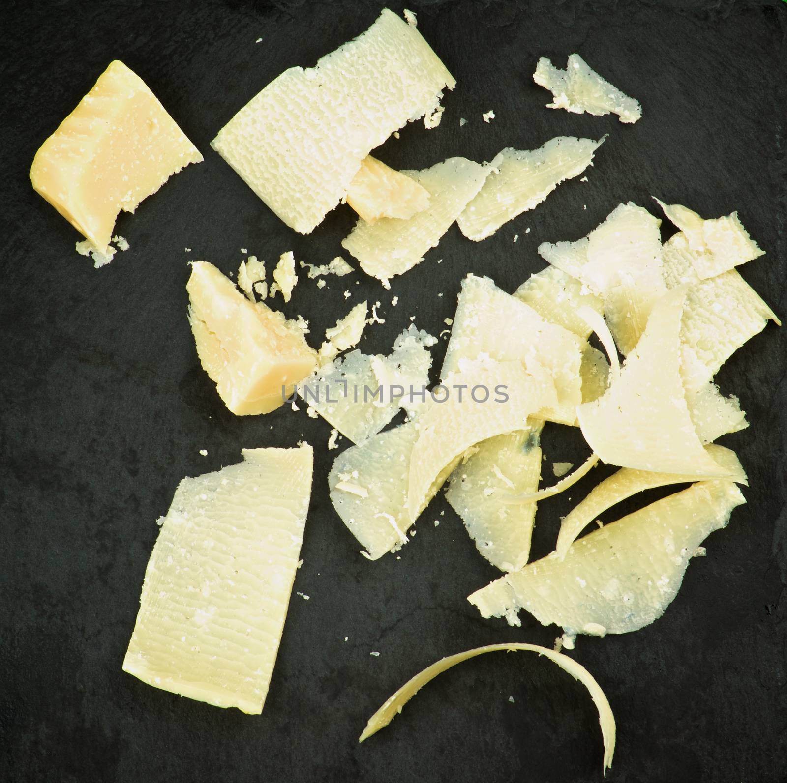 Slices of Gourmet Parmesan Cheese with Crumbs closeup on Black Stone background. Top View