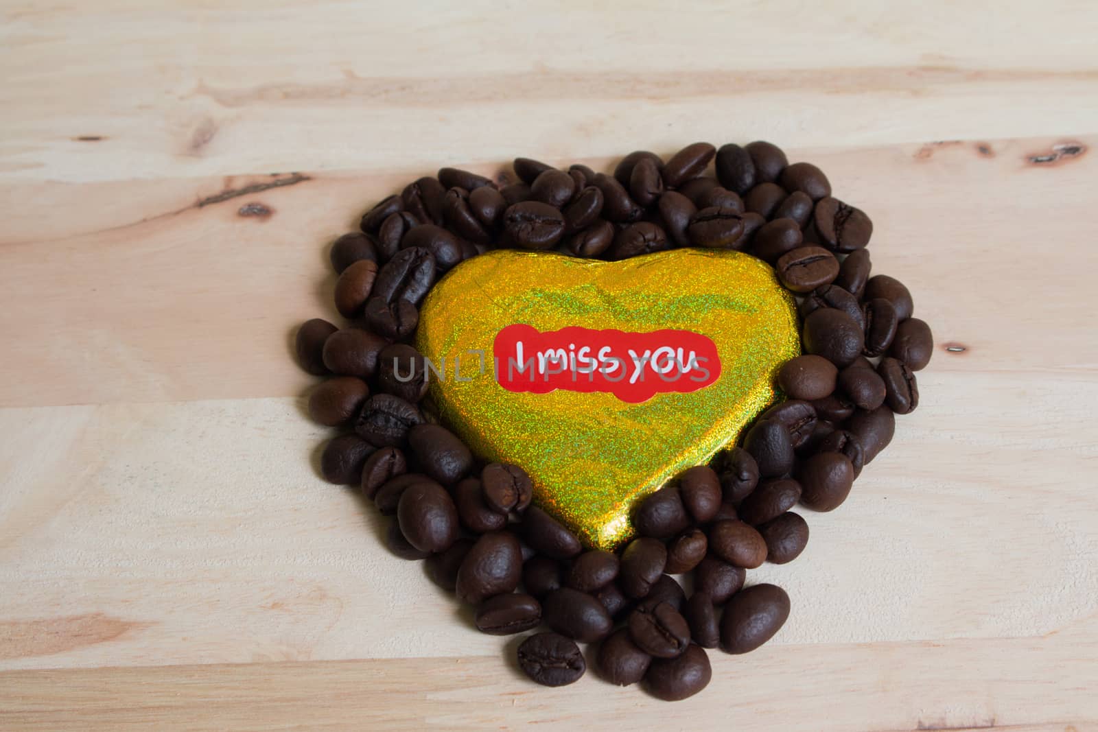 Coffee beans surrounded Chocolate wrapper on Valentine's Day, Wood background.