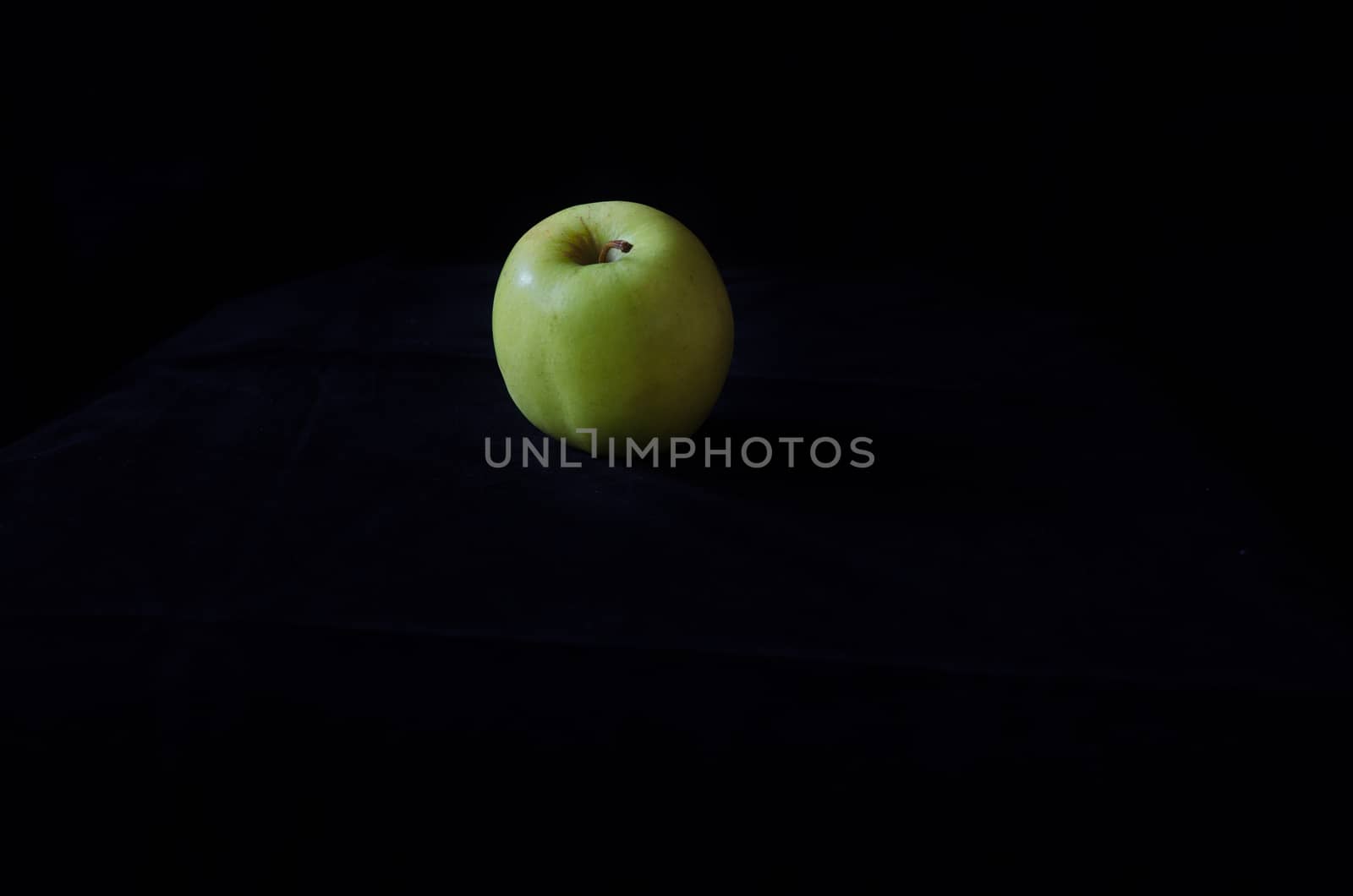 one green apple on a black background fresch and healty