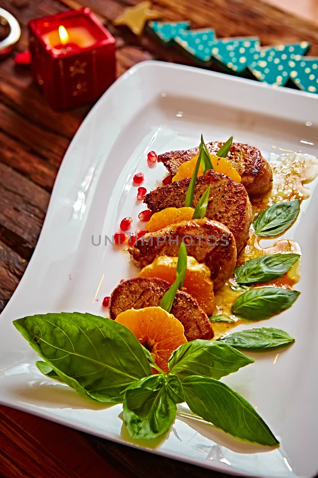 Grilled pork with mandarin oranges decorated with basil on a white plate