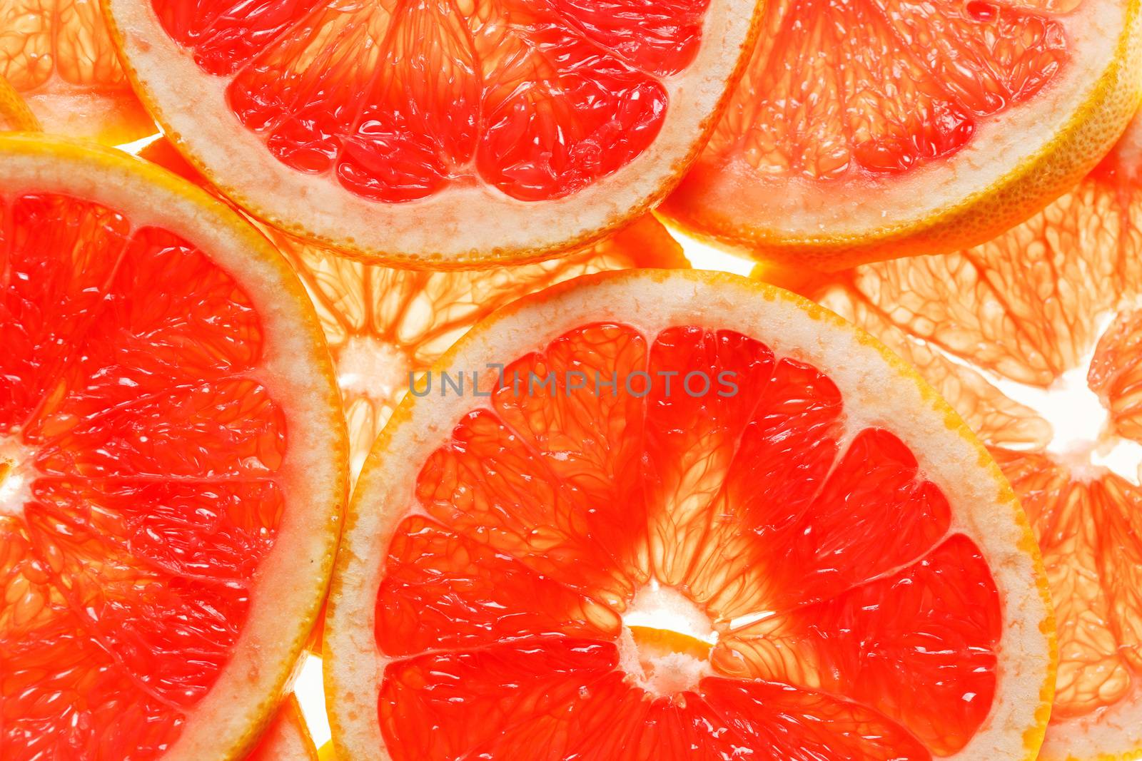 Transparent round pieces of red ripe juicy grapefruit background
