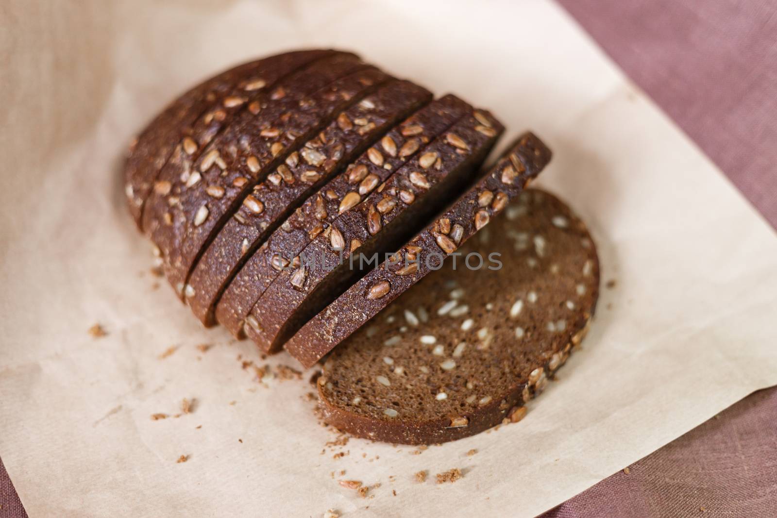 Sliced dark bread with crumbs on wood board