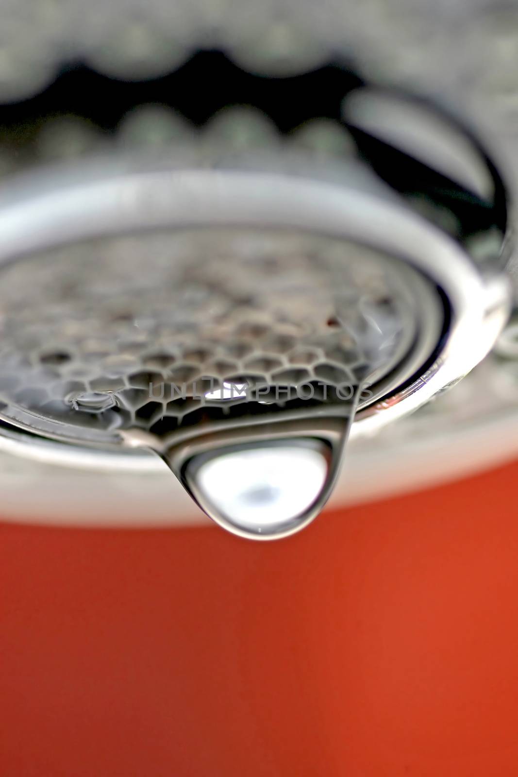 A macro of a white tap / faucet dripping with red background.