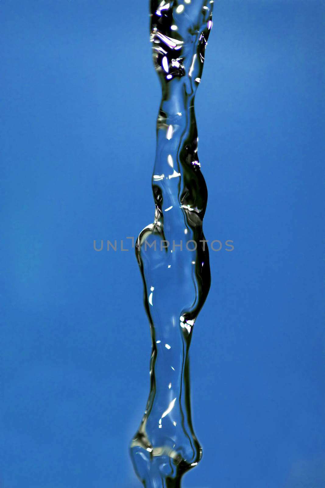 Water falling down, frozen in time with blue background.