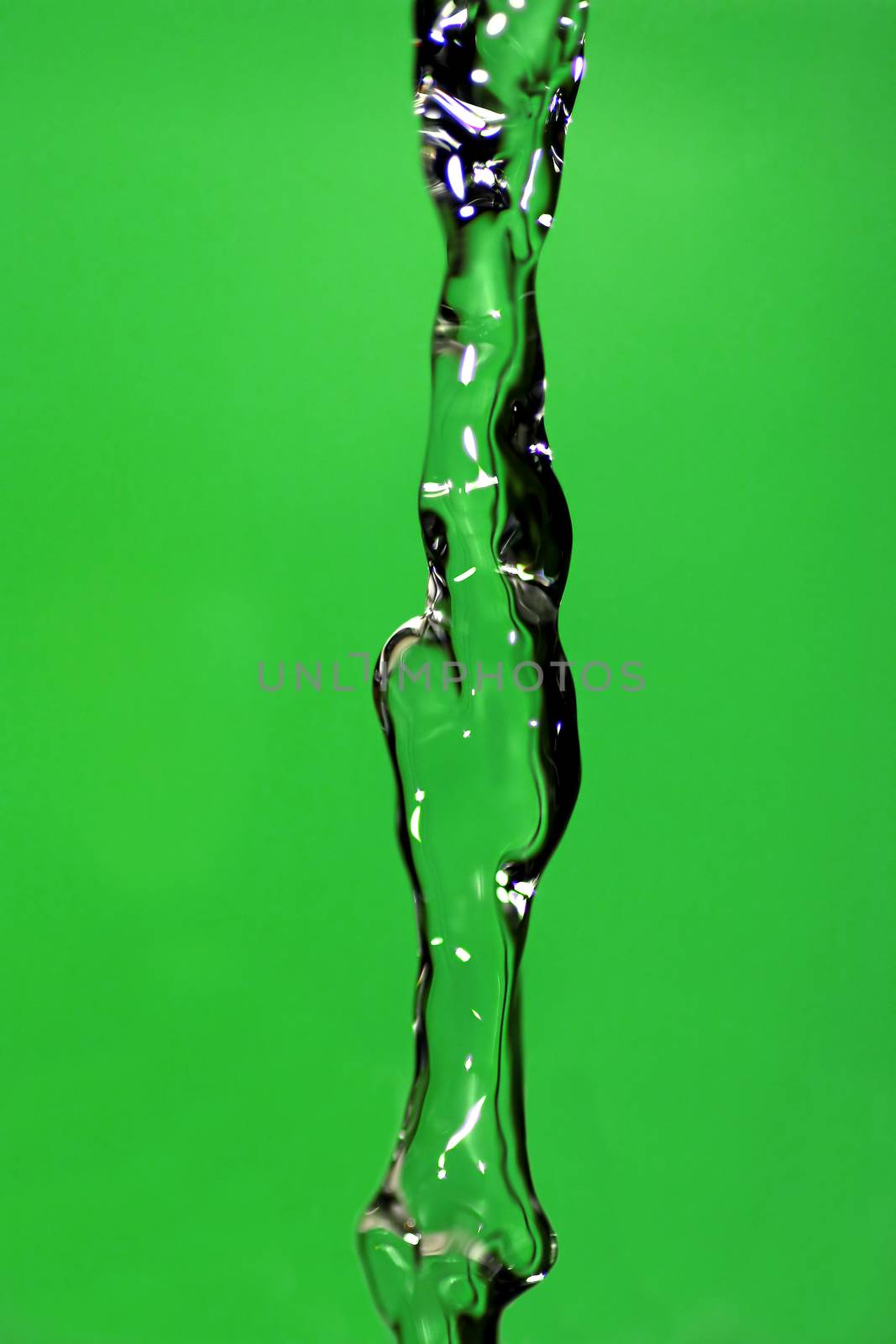 Water falling down, frozen in time with green background.