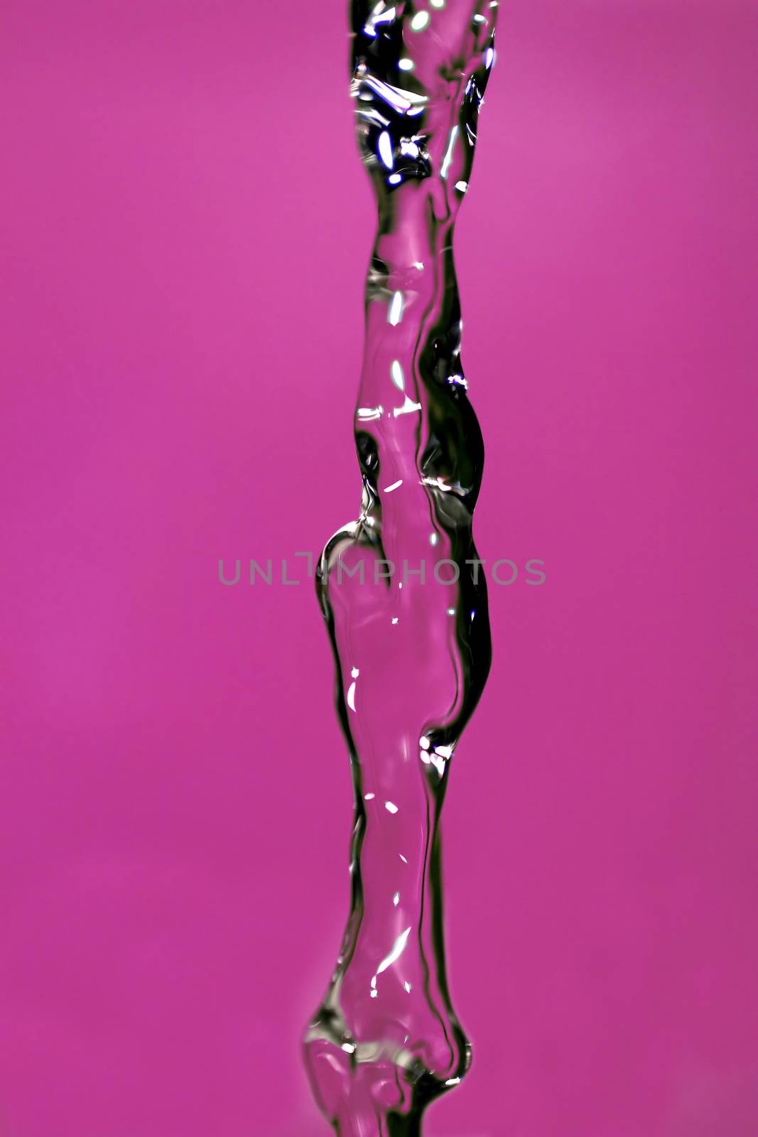 Water falling down, frozen in time with pink background.