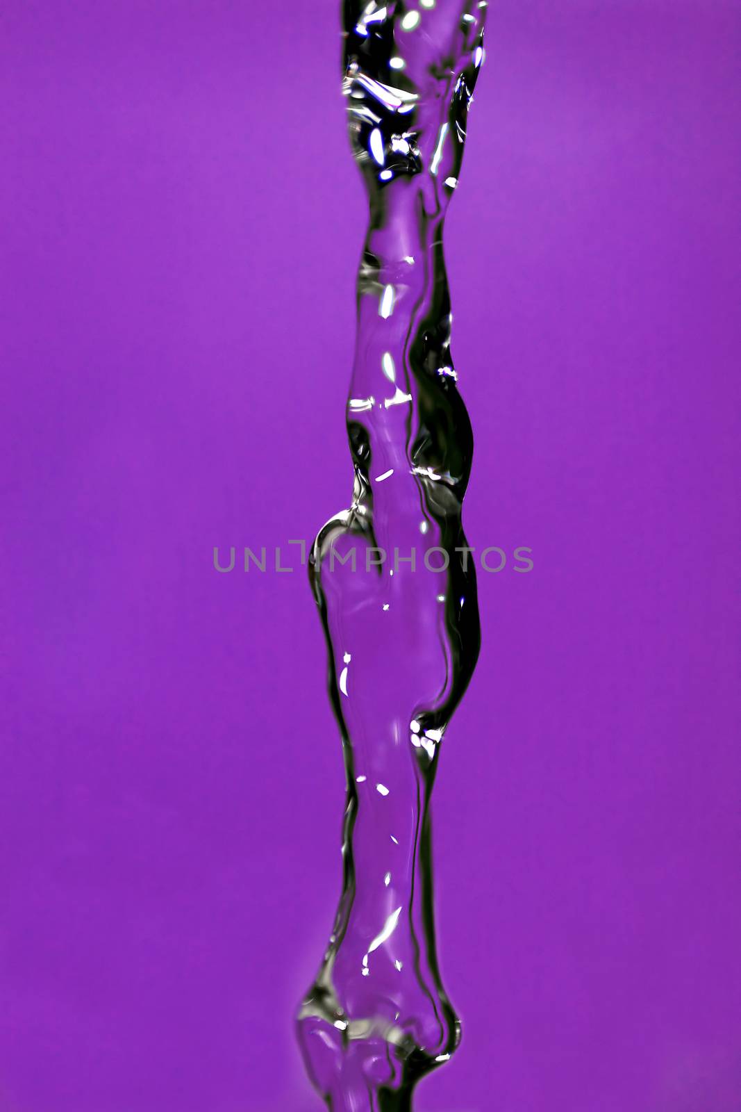 Water falling down, frozen in time with purple background.