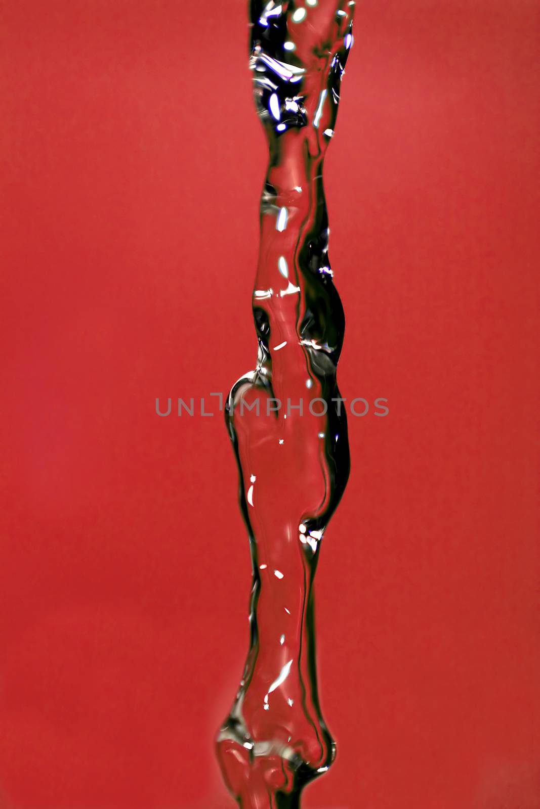 Water falling down, frozen in time with red background.