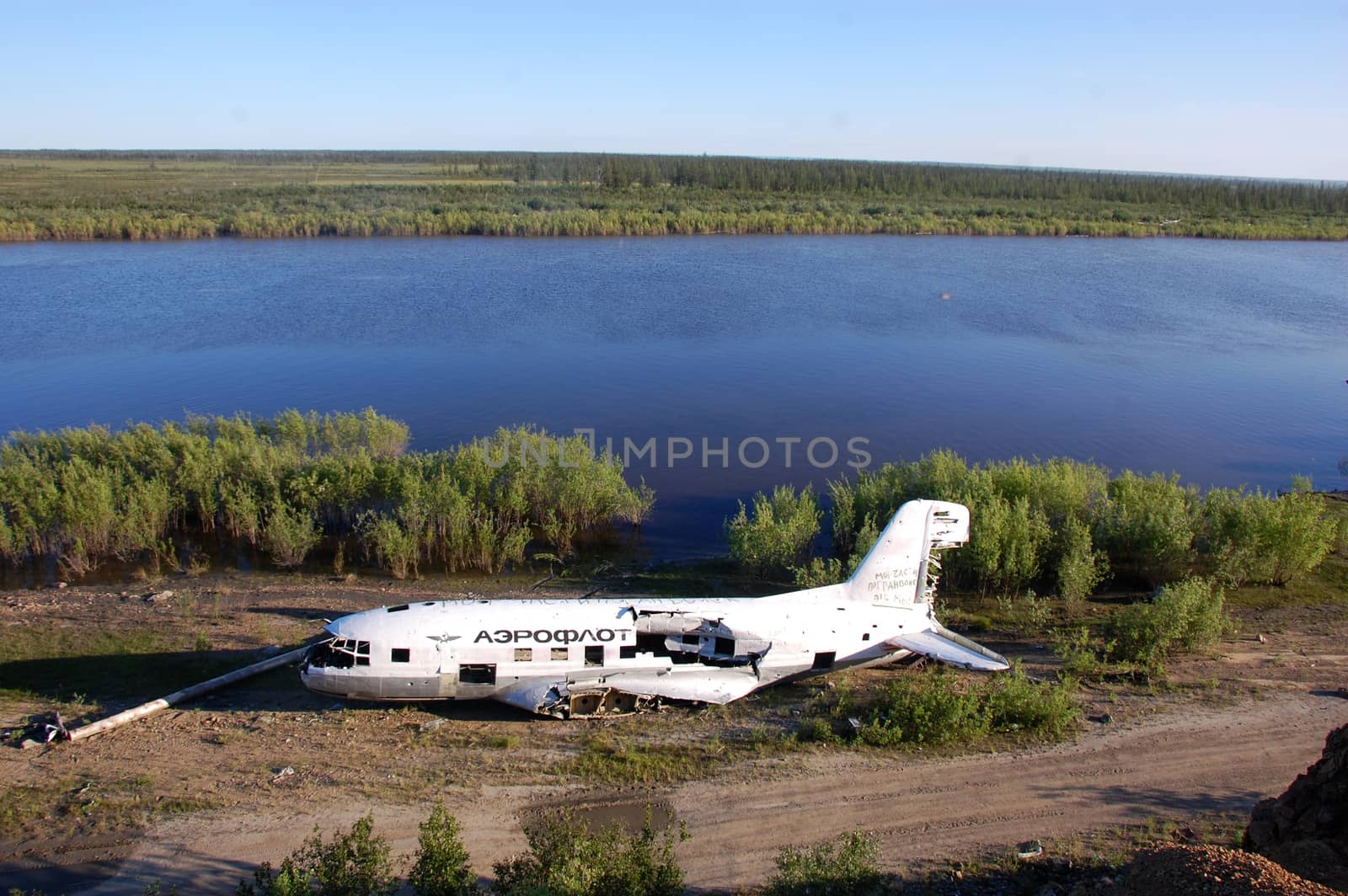 Broken abandoned airplane at Kolyma river coast by danemo