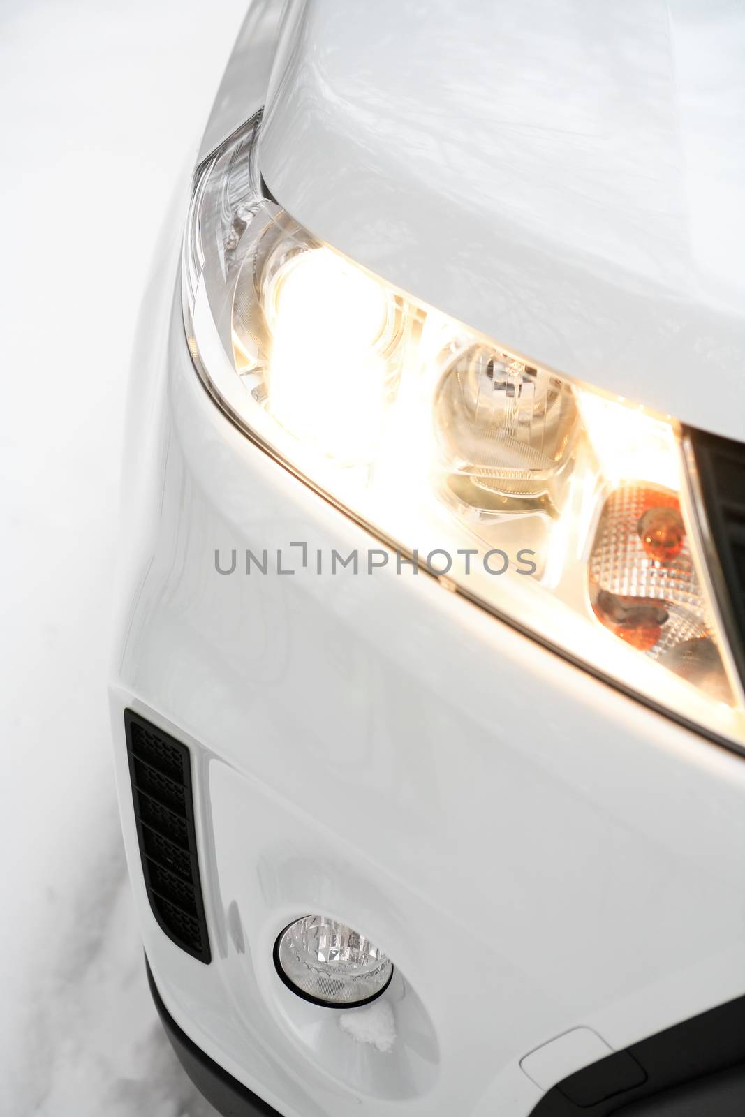 Closeup of new modern white car with lighting headlight