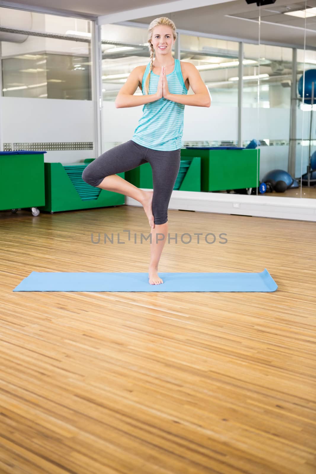 Fit woman doing yoga on mat in fitness studio