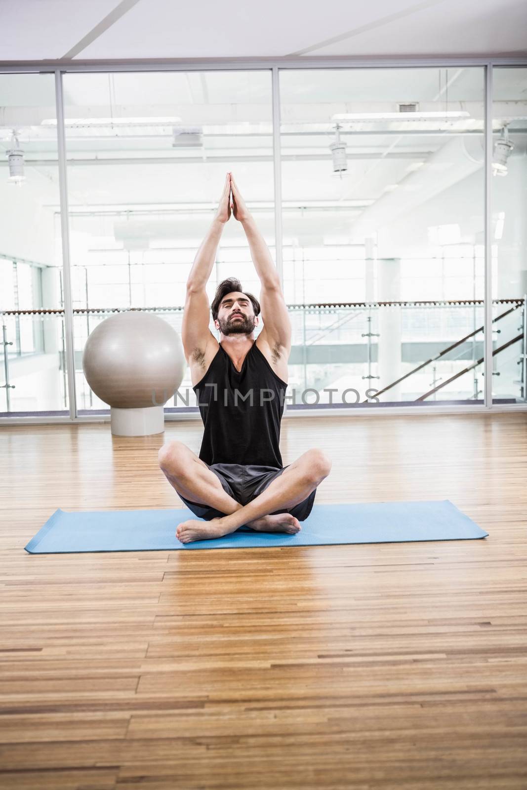 Handsome man doing yoga on mat by Wavebreakmedia