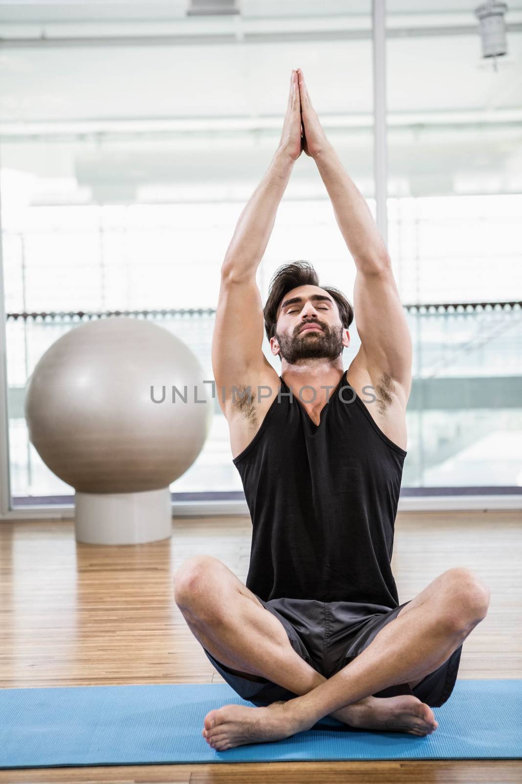 Handsome man doing yoga on mat in the studio