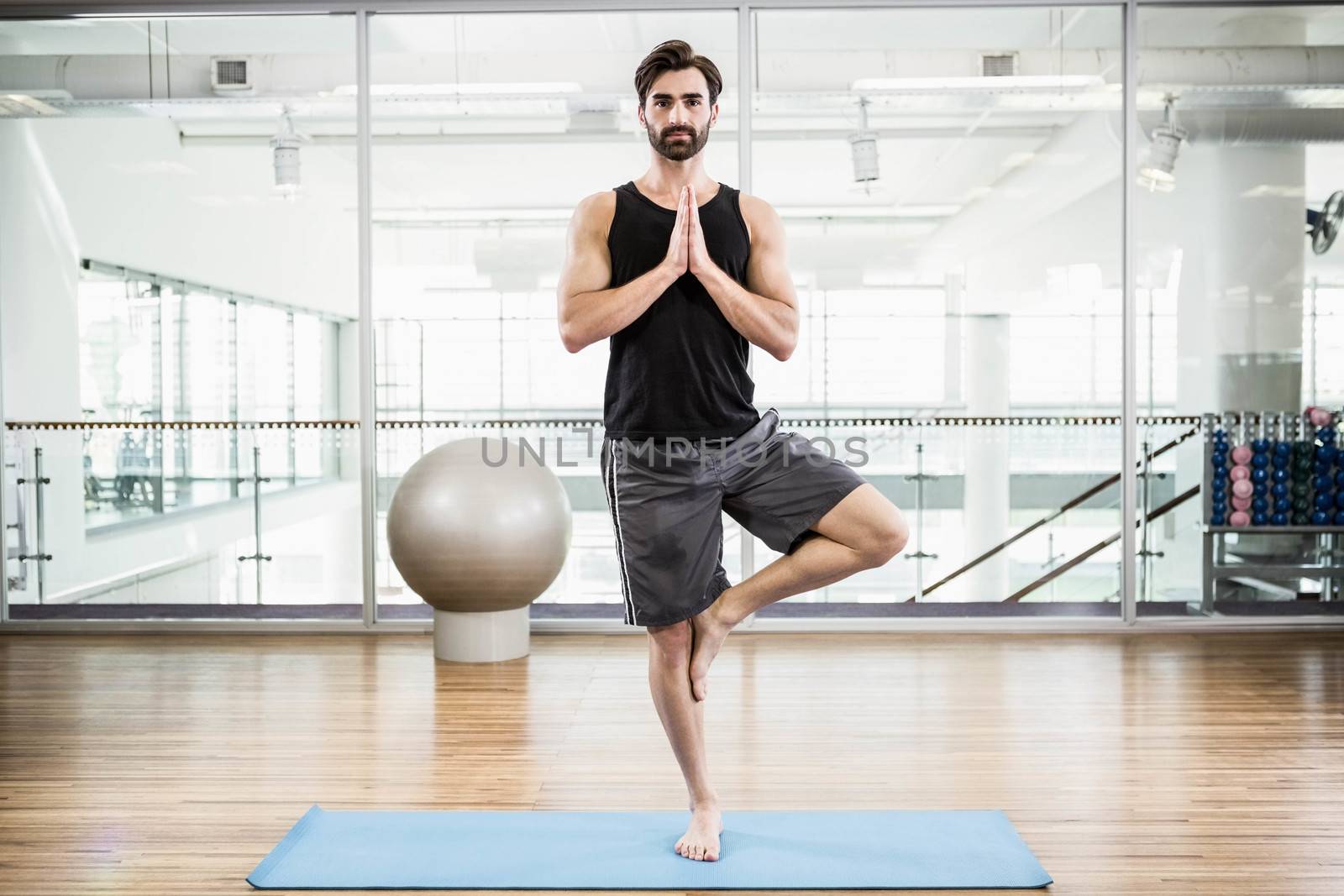 Handsome man doing yoga on mat in the studio