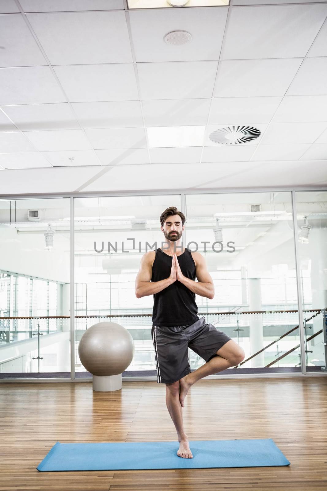 Handsome man doing yoga on mat in the studio