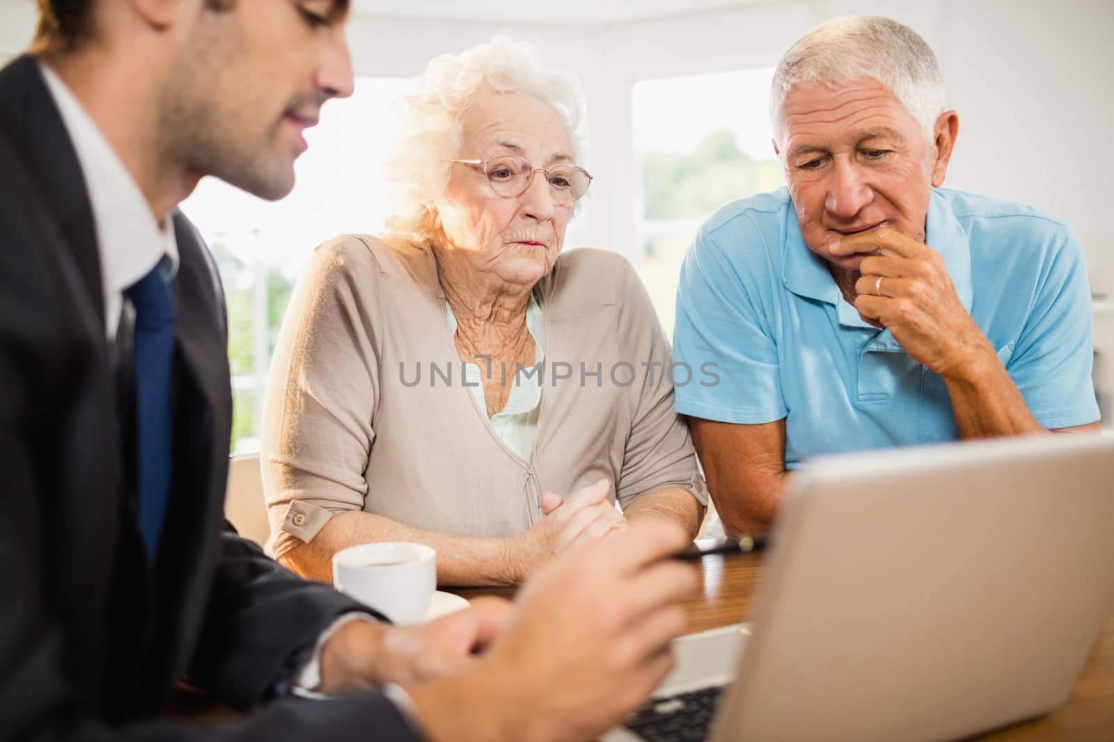 Businessman showing laptop to senior couple by Wavebreakmedia