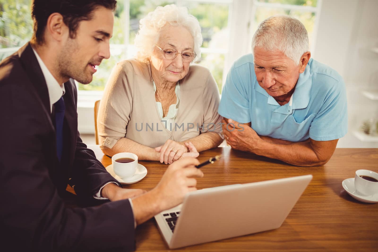 Businessman showing laptop to senior couple by Wavebreakmedia