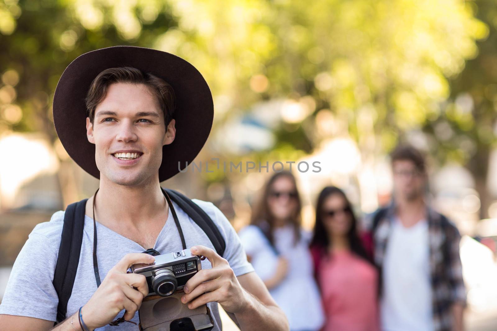 Hip man with digital camera smiling outdoors