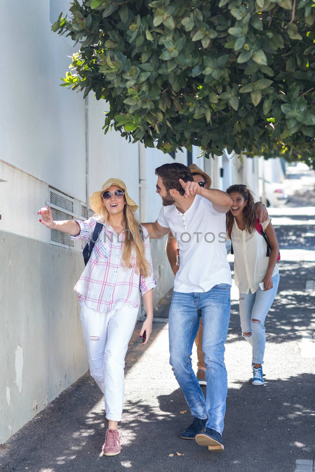 Hip friends walking on the street and pointing somewhere