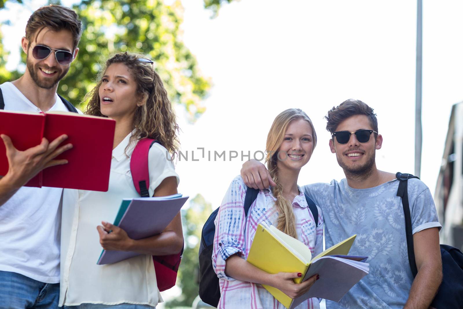 Hip friends reading notes on notebooks outdoors