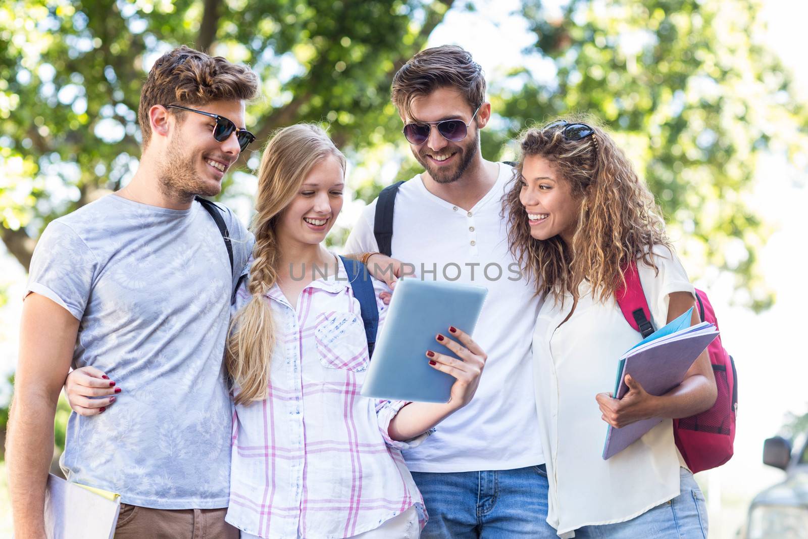 Hip friends looking at tablet outdoors