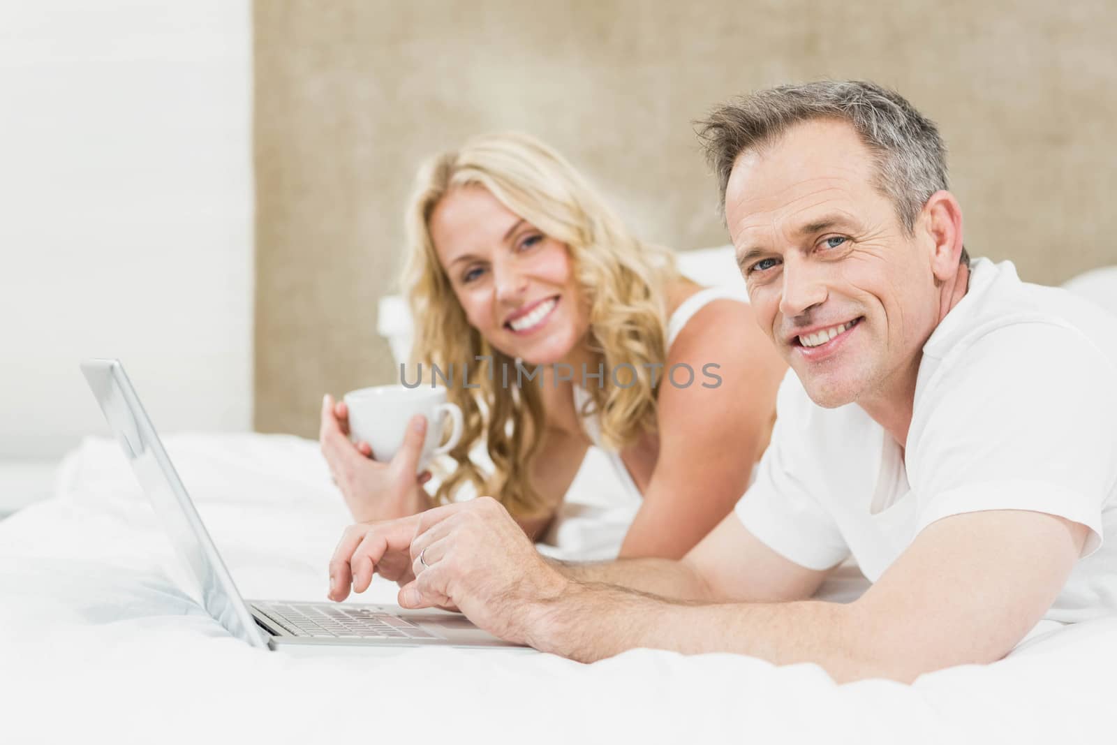 Cute couple using laptop in bed in their bedroom