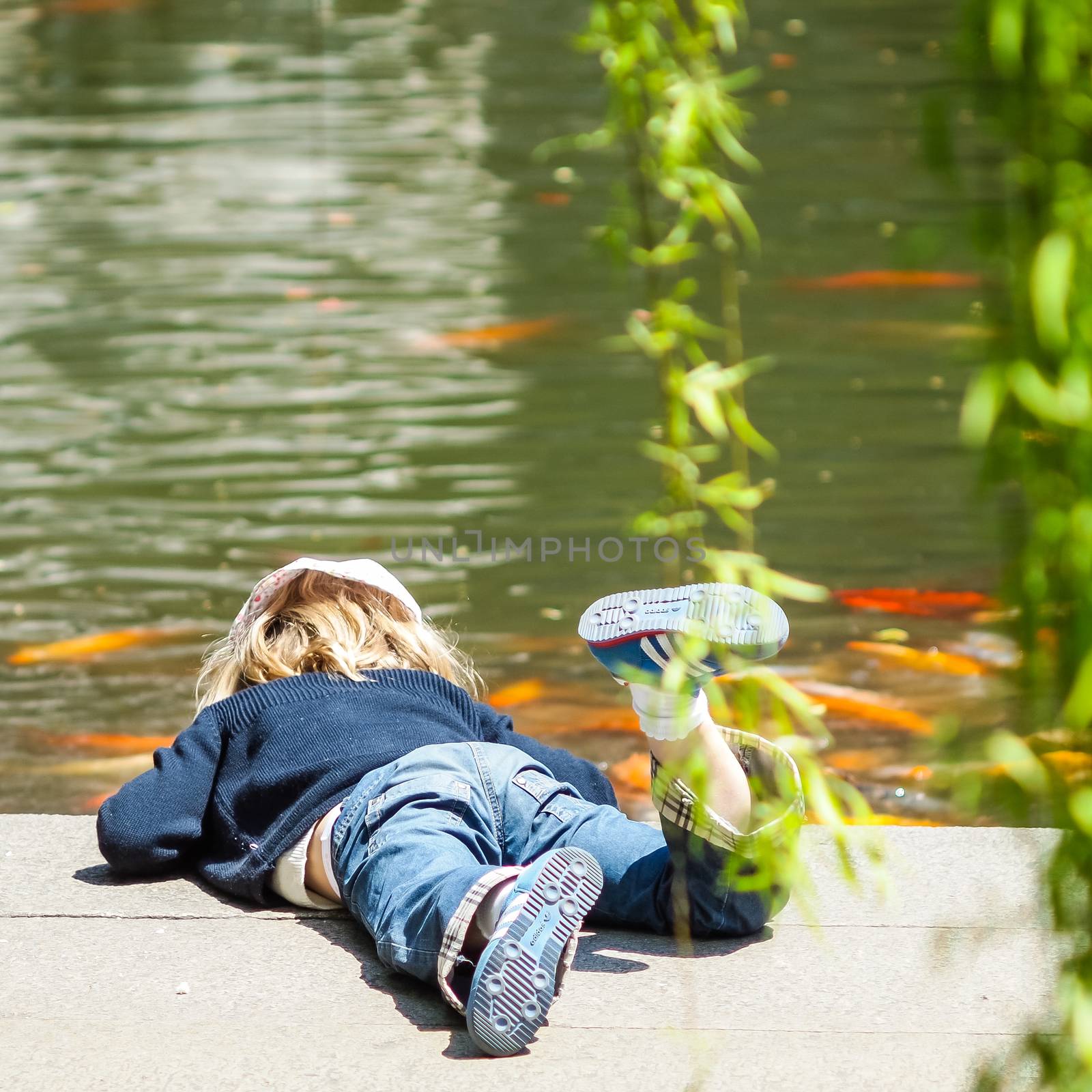 SHANGHAI, CHINA - April 12, 2011 : European girl in blue is playing with the carp fish in the pond.