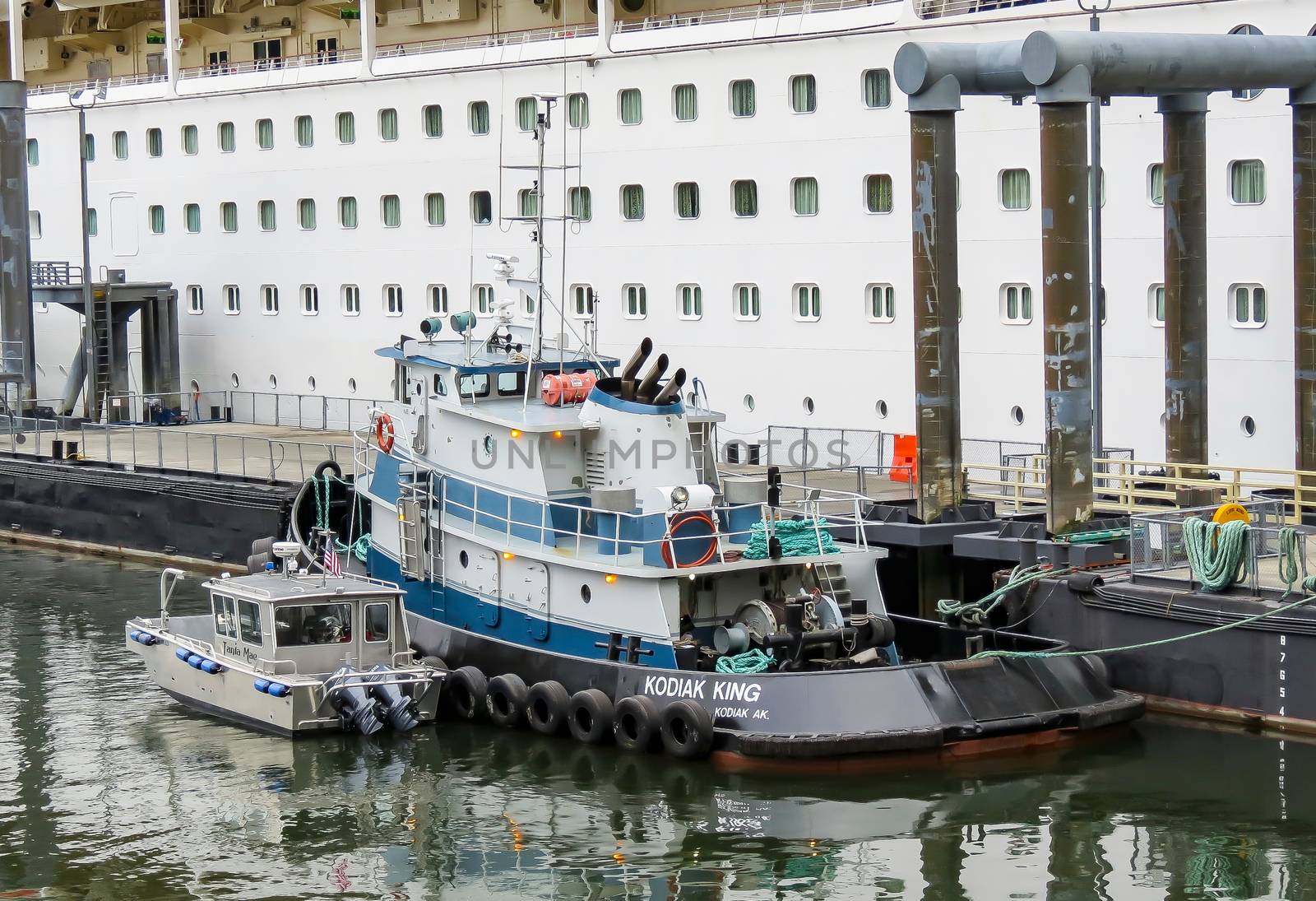 Juneau, Alaska, USA- June 17, 2012: A tugboat named "Kodiak King" sits along side a cruise ship after helping the large boat navigate and dock in the harbor in this popular tourist location in the summer.