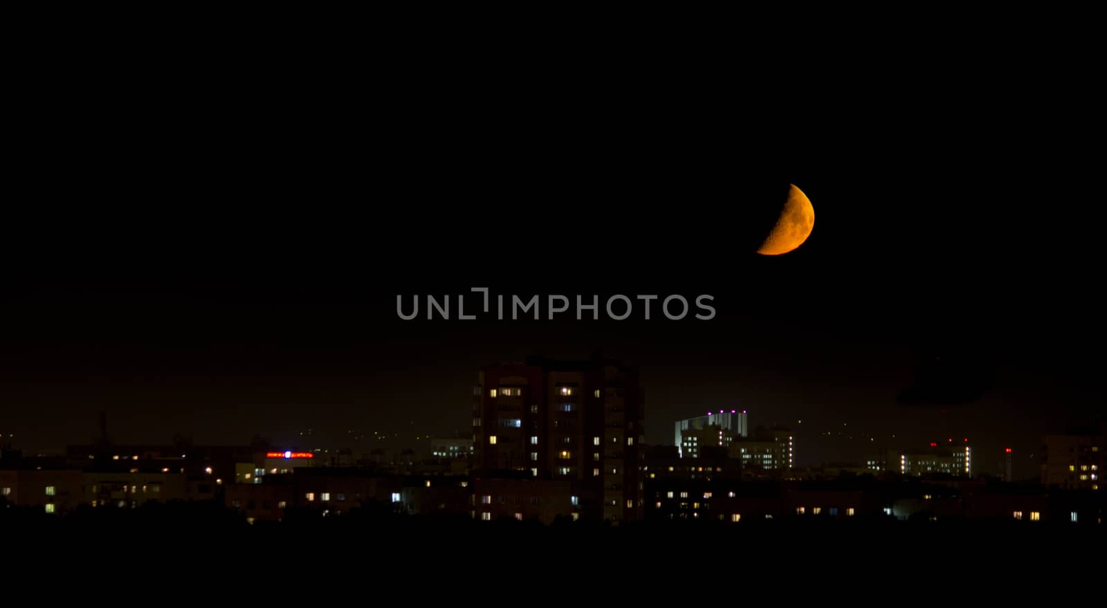 big bloody moon near the horizon in the city