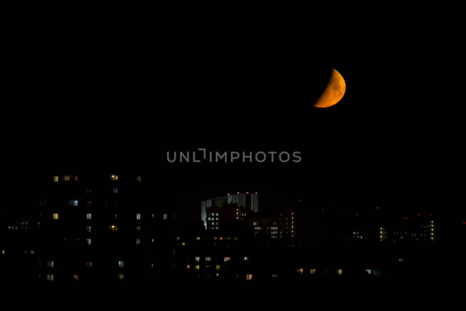big bloody moon near the horizon in the city