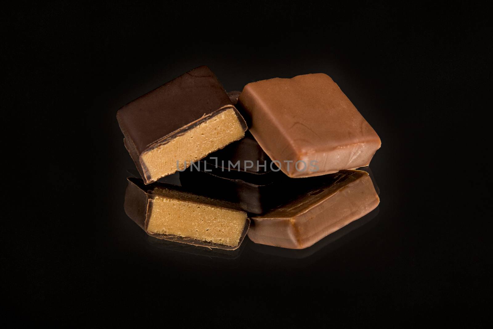 Chocolate sweets collection on black background reflected on mirror