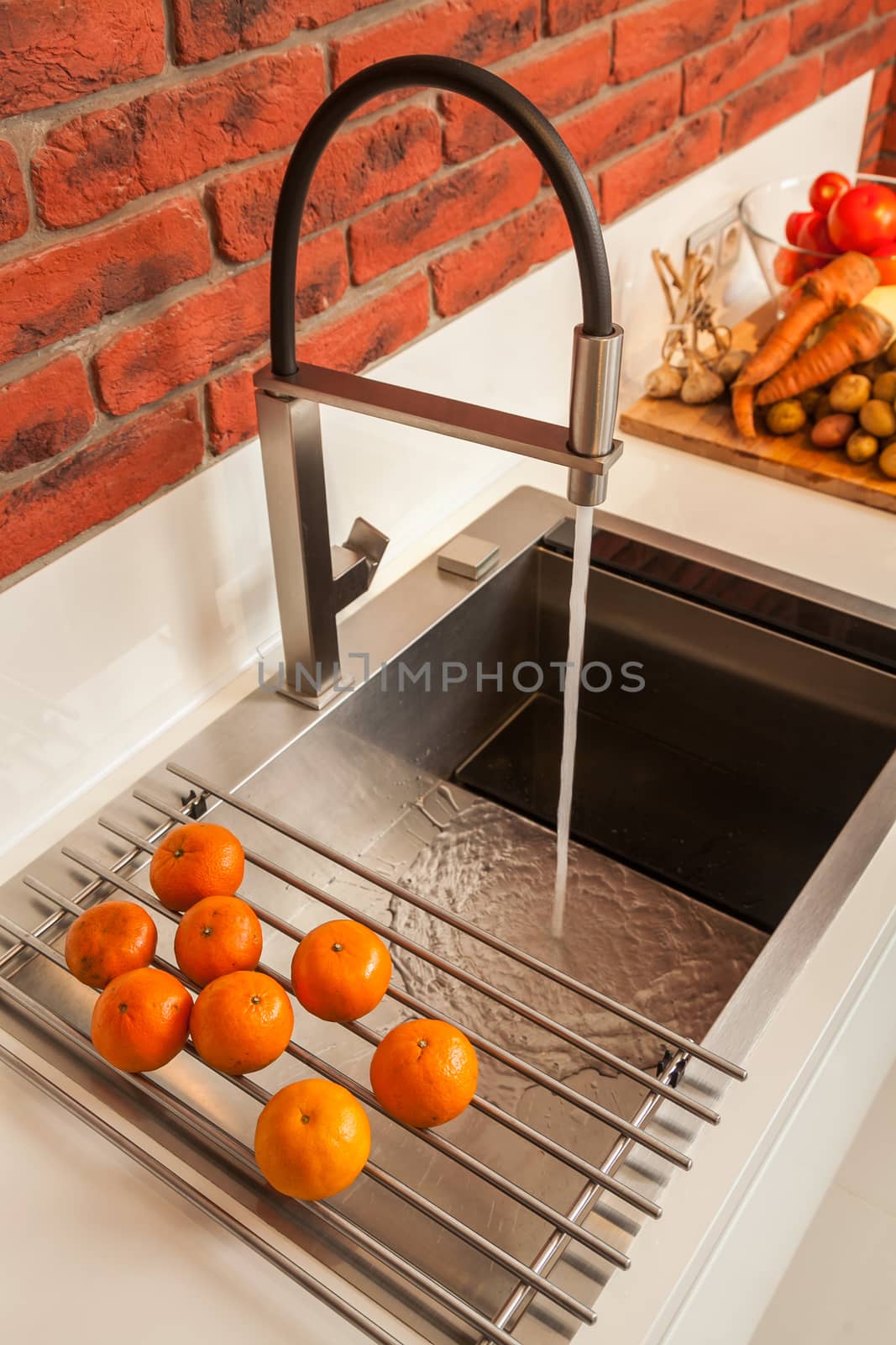 Fragment of modern kitchen with a sink and the mixer and a row the lying vegetables