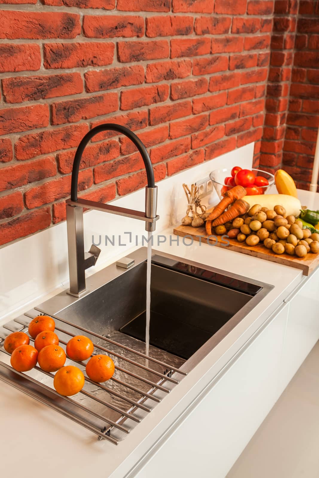 Fragment of modern kitchen with a sink and the mixer and a row the lying vegetables