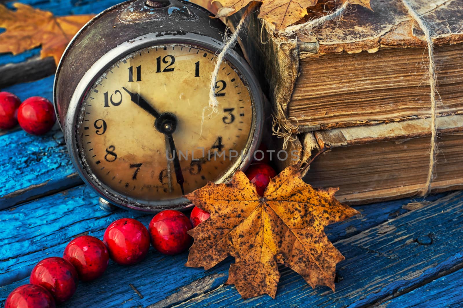 old-fashioned alarm clock and coral beads on a light blue wooden background