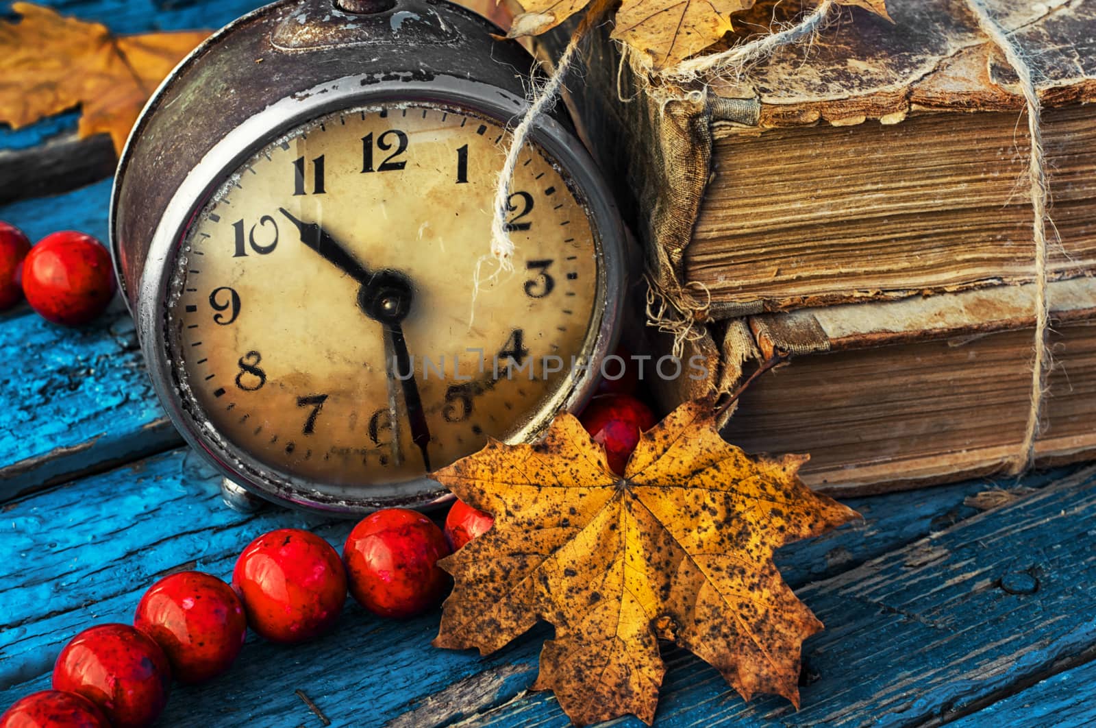 old-fashioned alarm clock and coral beads on a light blue wooden background