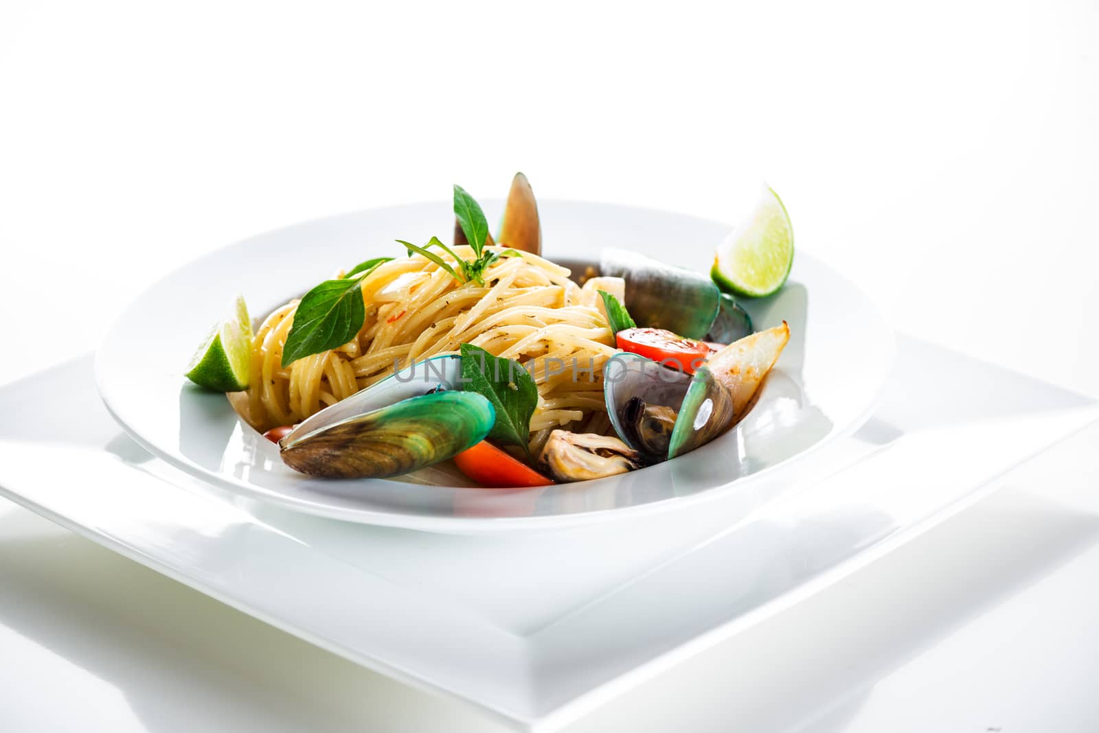 Fresh and spicy seafood pasta in white plate on white background