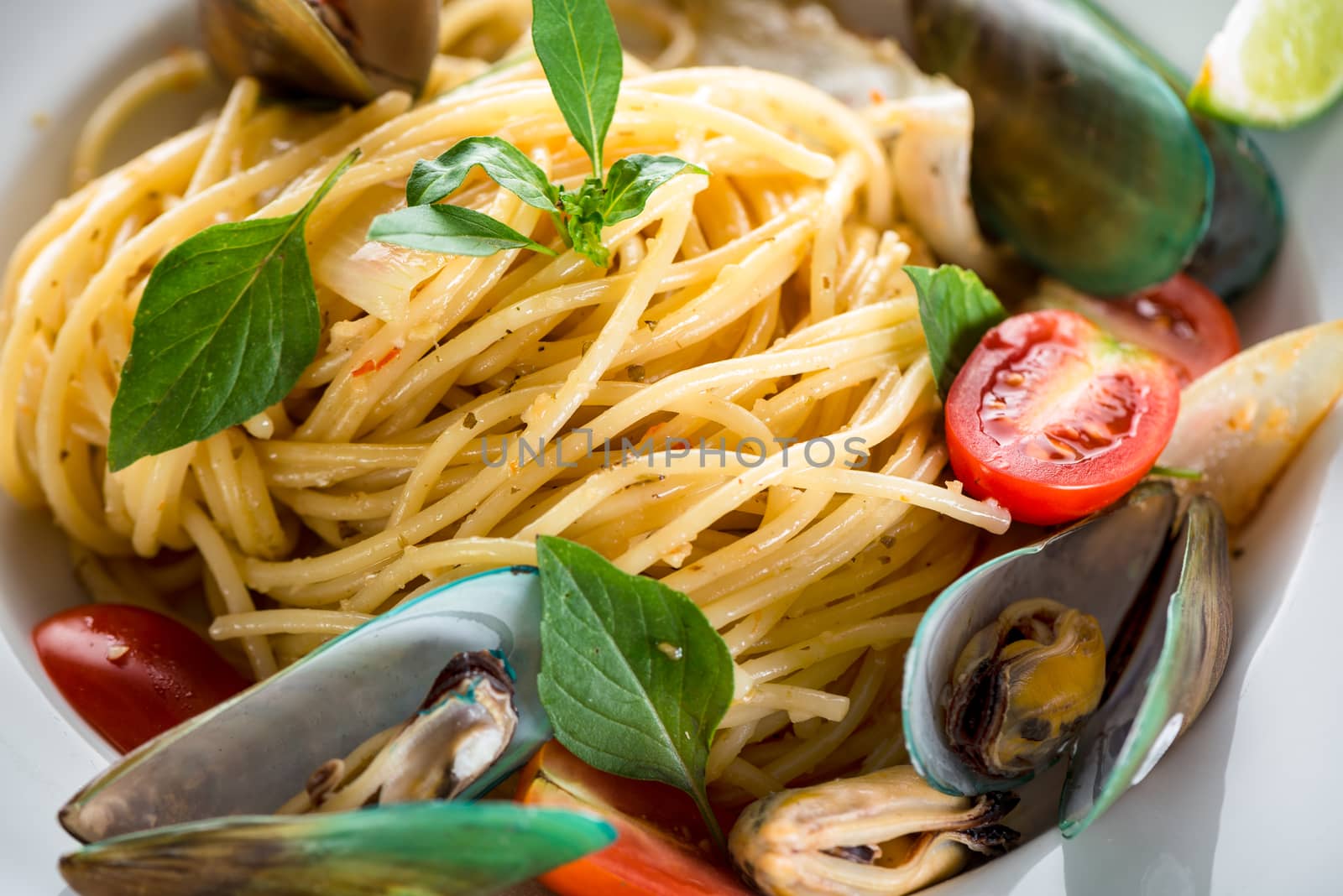 Fresh and spicy seafood pasta in white plate on white background