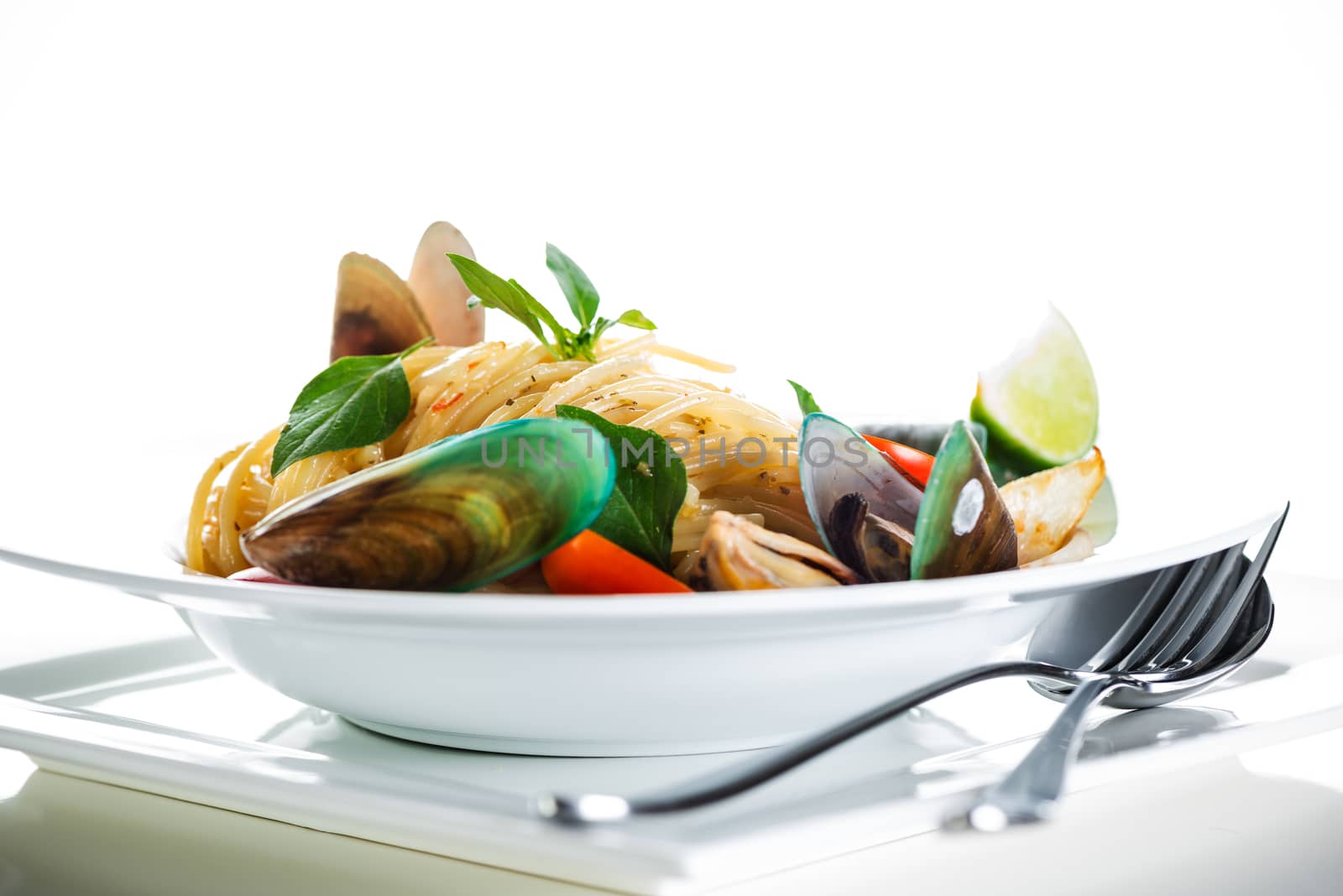 Fresh and spicy seafood pasta in white plate on white background