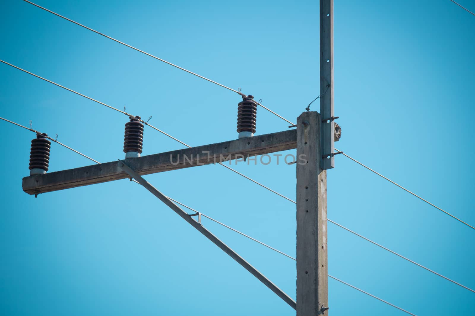 concrete electric pole on blue sky by chingraph