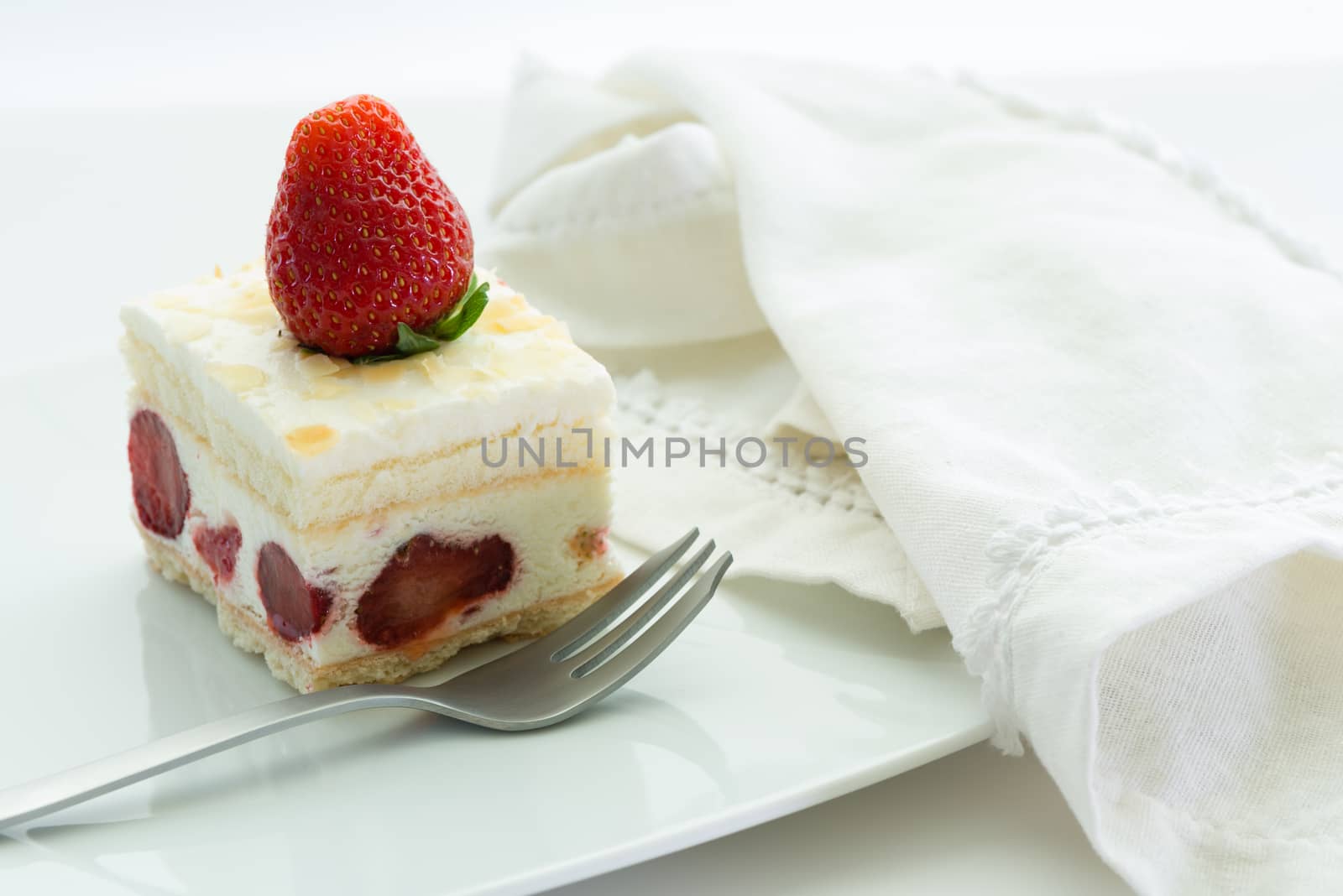 Dessert - sweet strawberry cake on white plate and white napkin