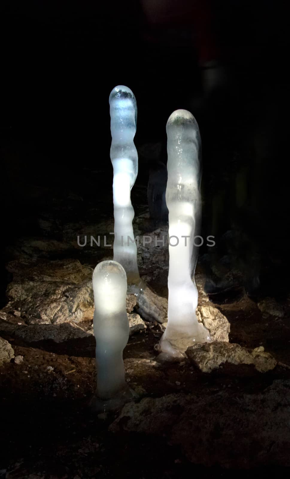 Luminescent ice stalagmites in the cave. by vapi