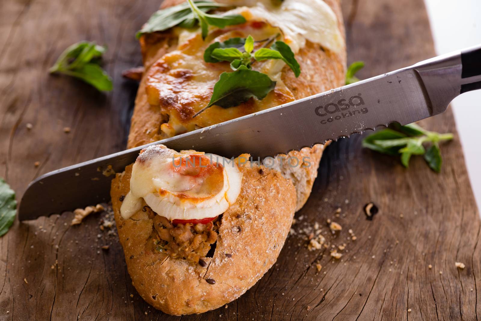 pizza baguette with mozzarella onion and tuna decorated with basil leafs
