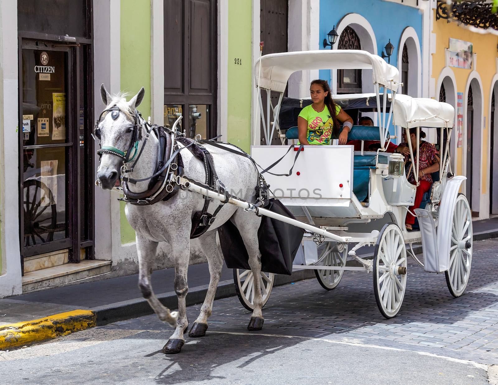 San Juan, Puerto Rico- June 16, 2013: A couple of tourists or locals are enjoying a unique old fashioned horse and buggy ride in historic Old San Juan, Puerto Rico.