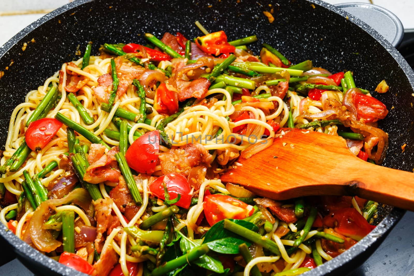 Spaghetti with asparagus tomatoes bacon and herbs in a pan